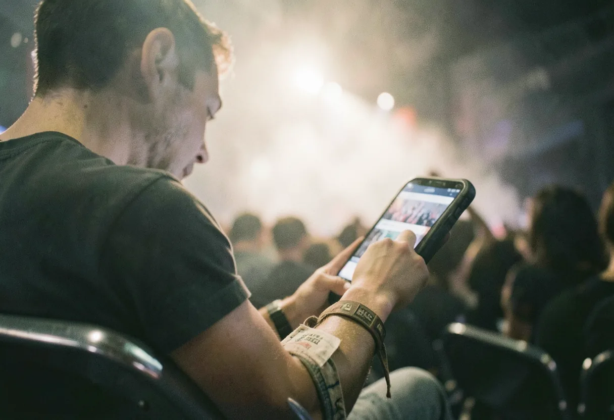 Concertgoer checking phone under soft lighting, concert reviews.